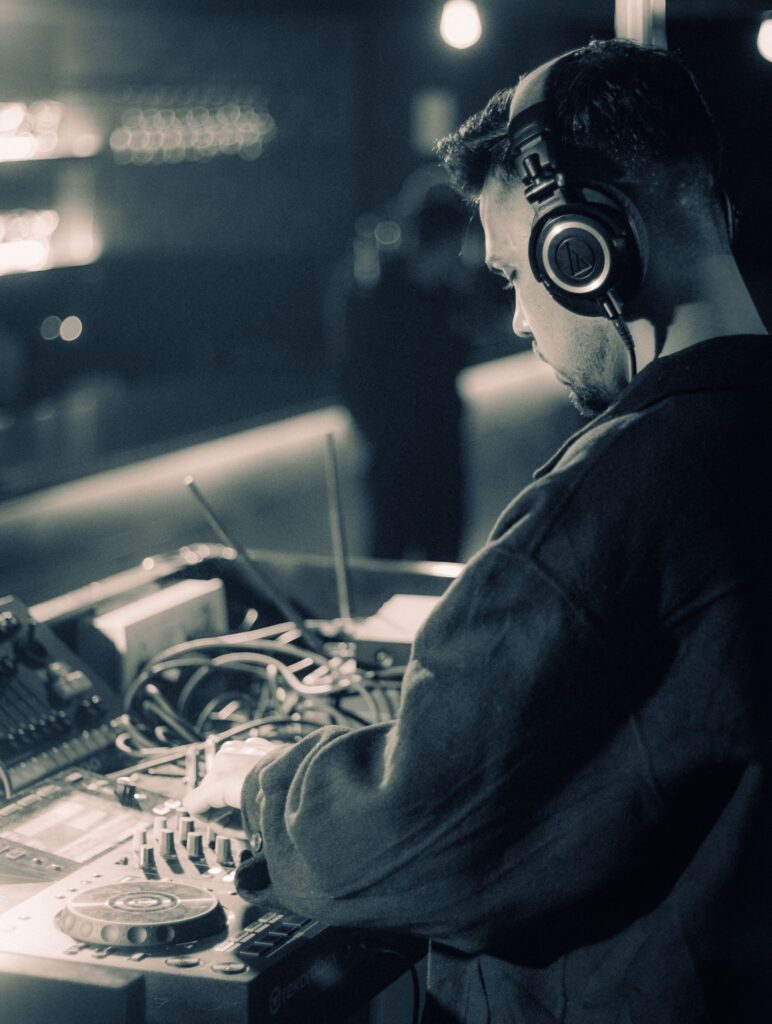 DJ wearing headphones mixes music at an intimate nightclub setting.